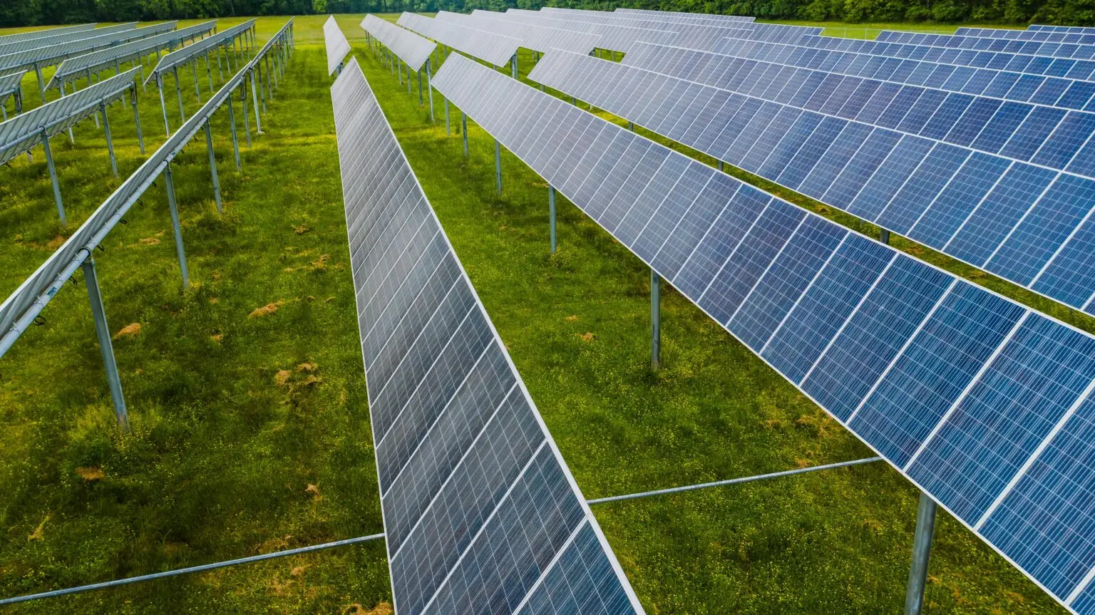 An aerial view of solar panels arranged in a green field